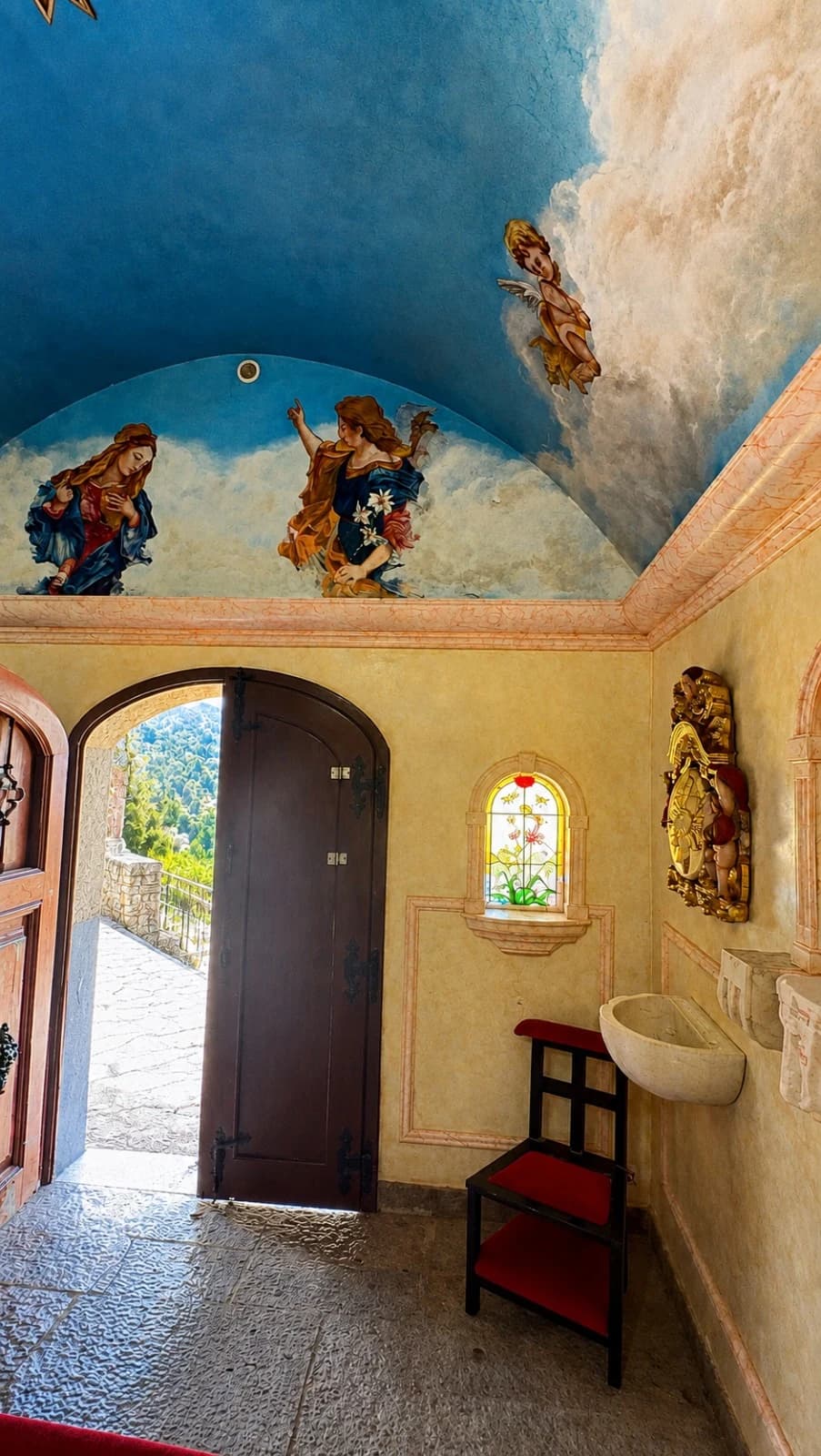 Entrada da capela com frescos pintados e vitral
